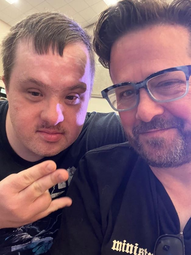 Two guys one trying to put two fingers up in a peace sign