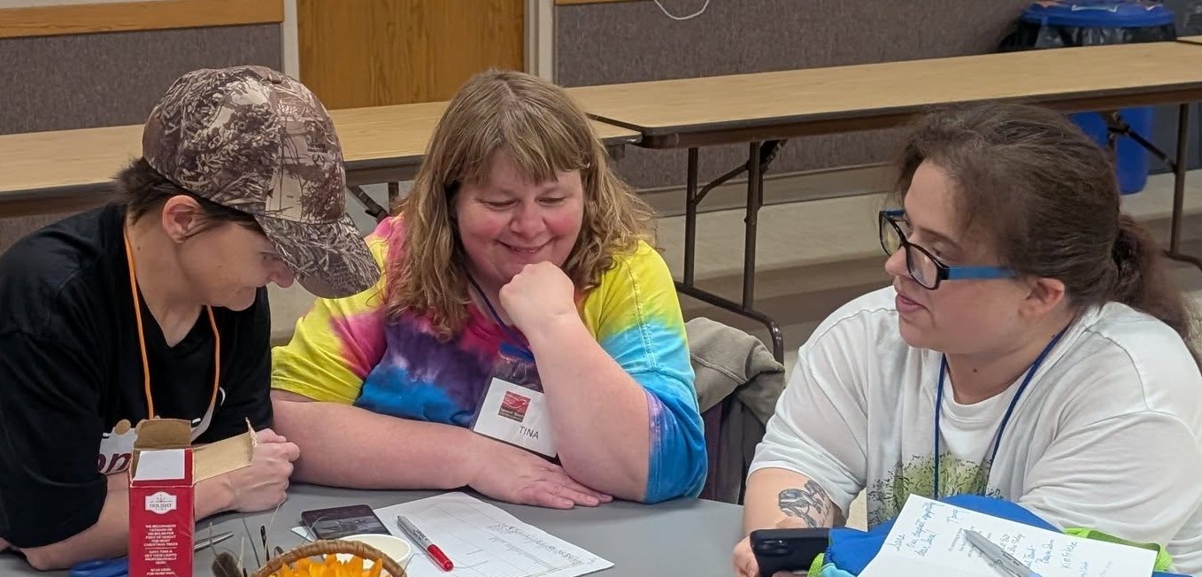 Three women gathering around a table smiling and talking.