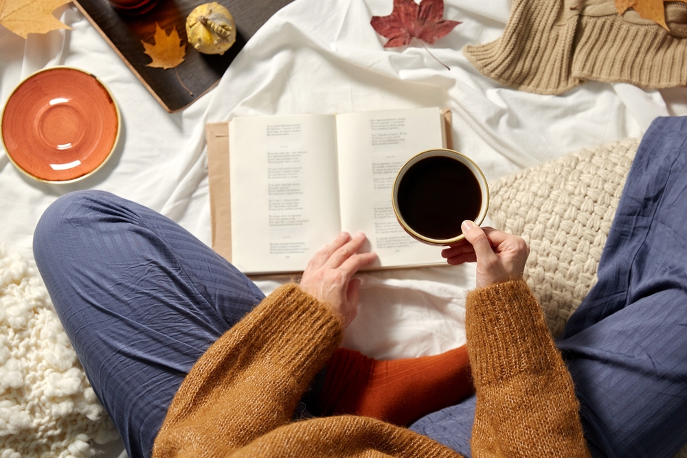 Person Reading a book with a cup of coffee or tea