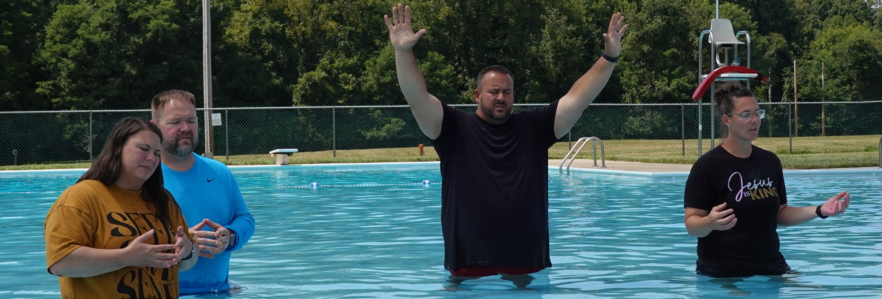 Rev. Tracie Corll and other people praising God in the water during baptism.