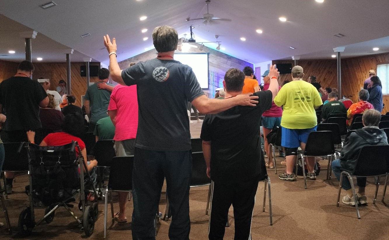 A group of people including a young man and an adult, worshipping in a chapel