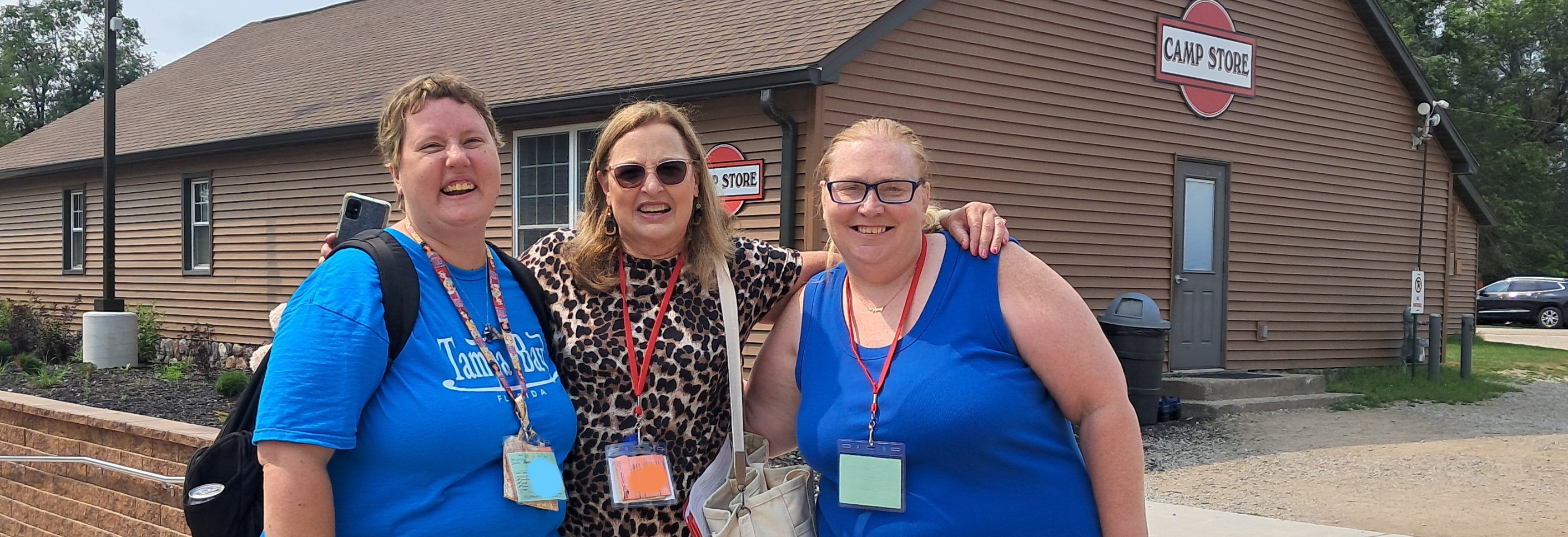 three woman in front of the camp store smiling posing for a photo moment