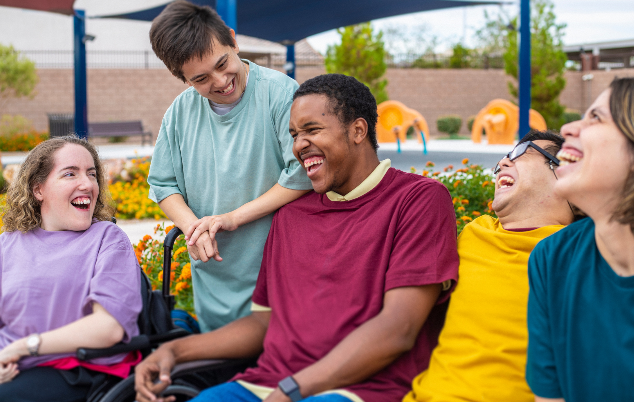 A group of youth some with an obvious disability laughing in a group