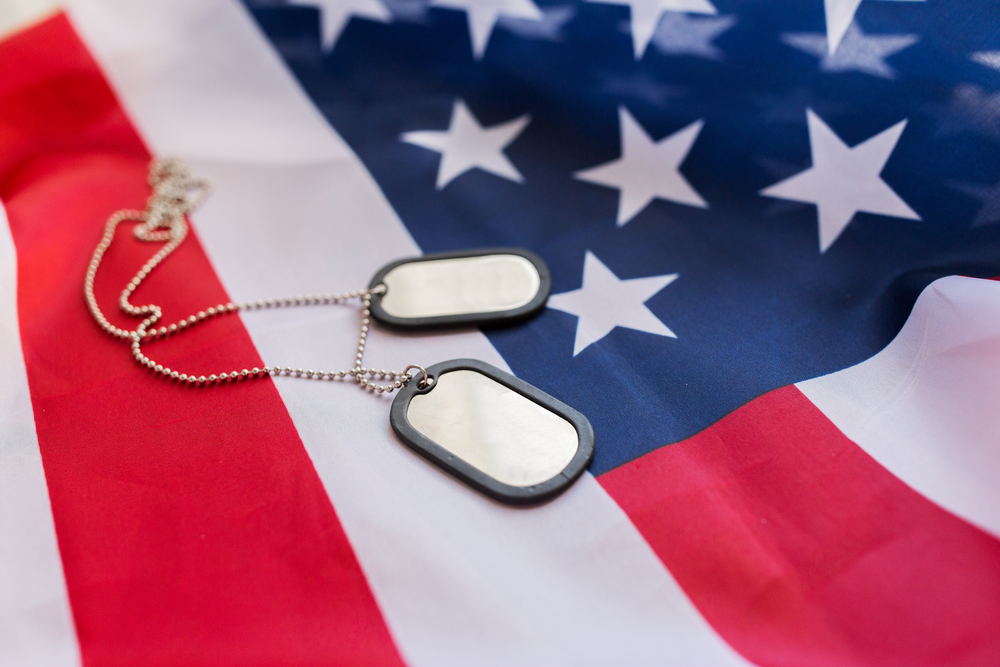 American flag with two military dog tags resting on it