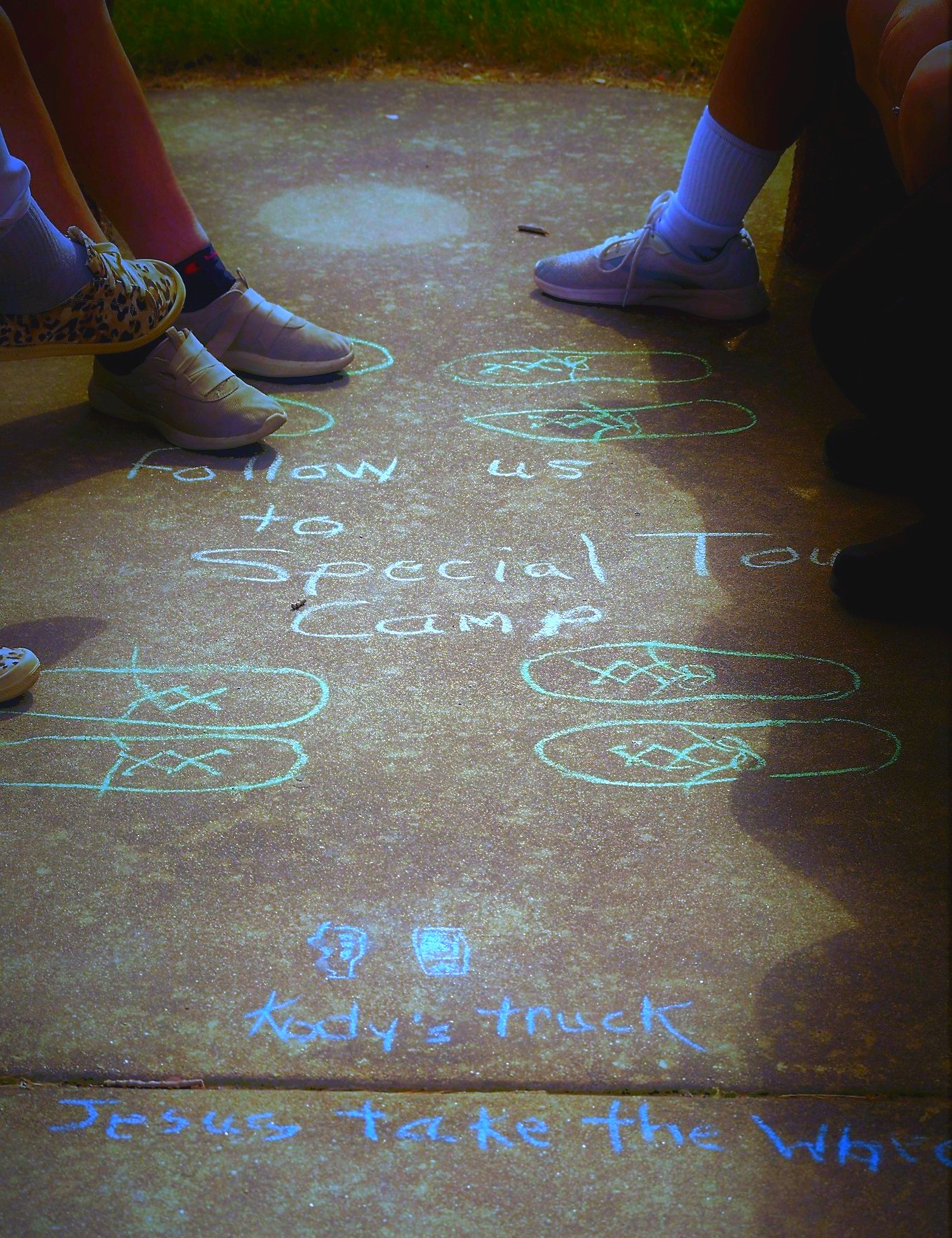 Chalked sidewalk with Follow us to Special Touch Camp and pictures of shoes