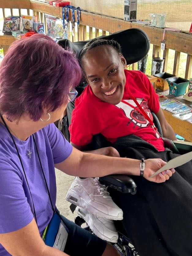 Staff holding a paper for a guest using a wheelchair smiling