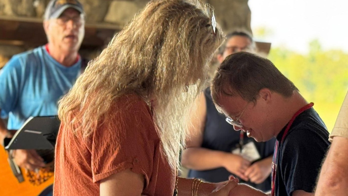 A woman praying with another person during worship service.