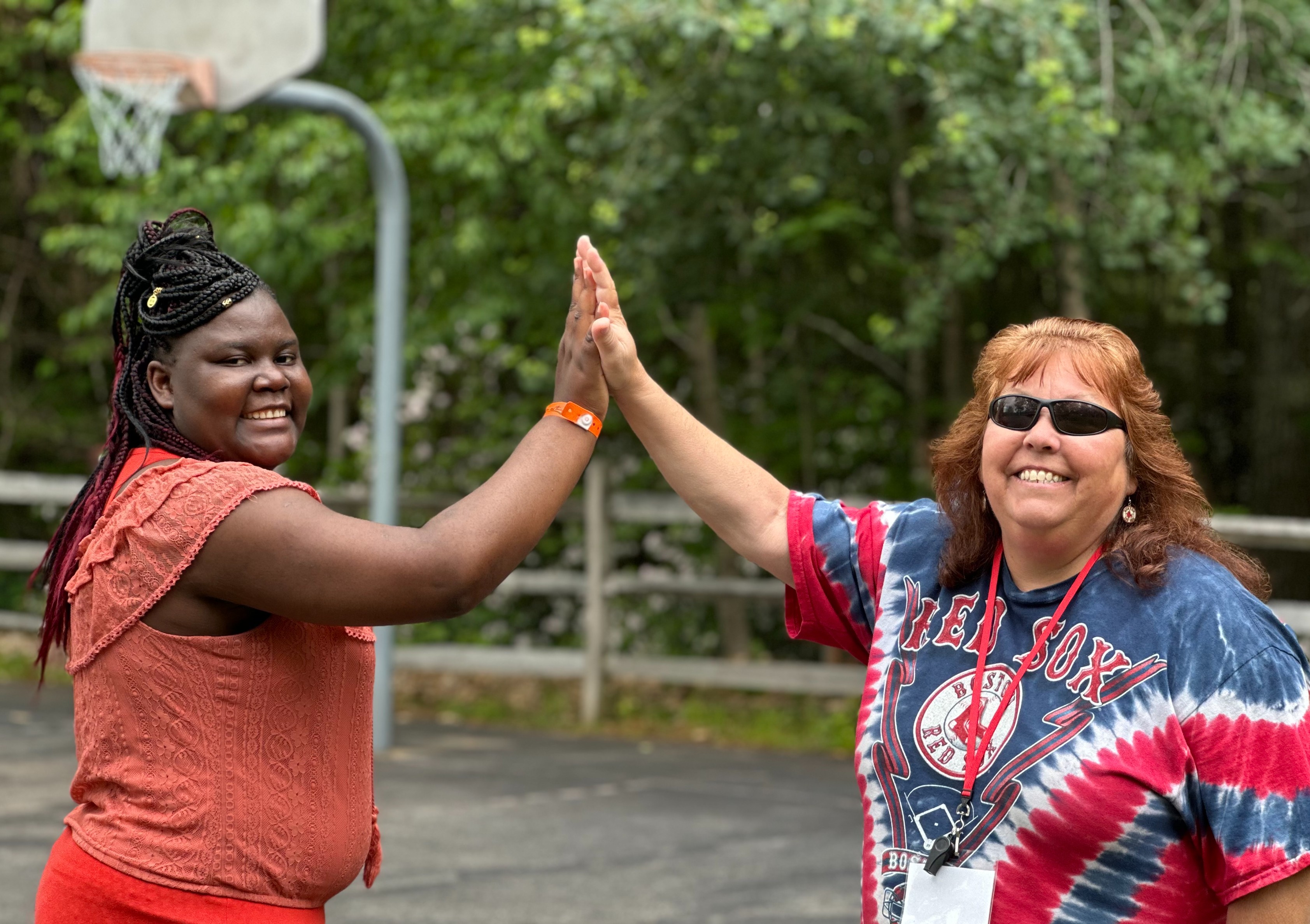 two woman high five in front of basketball hoop