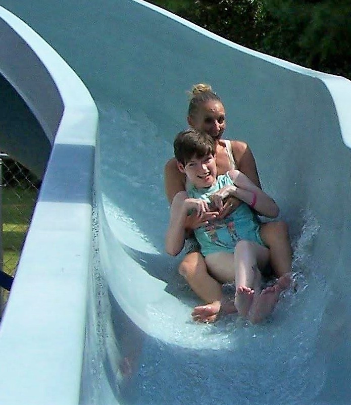 Woman with girl in front of her going down a waterslide together