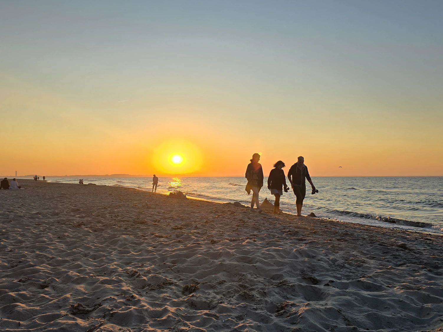 Strand bei Sonnenuntergang mit Menschen an der Ostsee