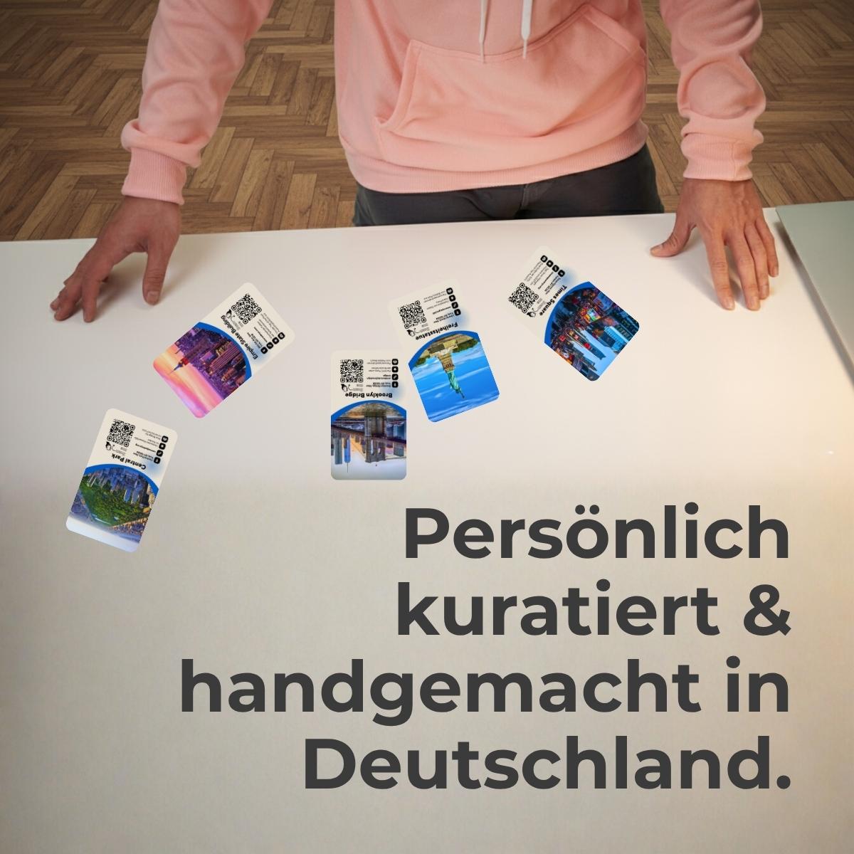 Stefan Berndt mit apricotfarbenem Hoodie legt Entdeckerkarten auf einen Tisch – Schriftzug „Persönlich kuratiert & handgemacht in Deutschland“