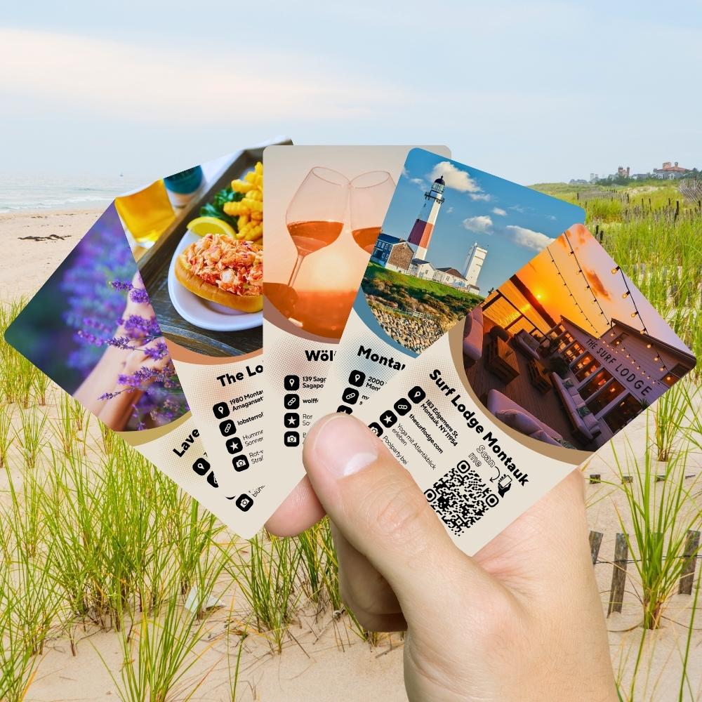 Hand hält Entdeckerkarten „New York – Die Hamptons“ mit Strandmotiven und Sehenswürdigkeiten