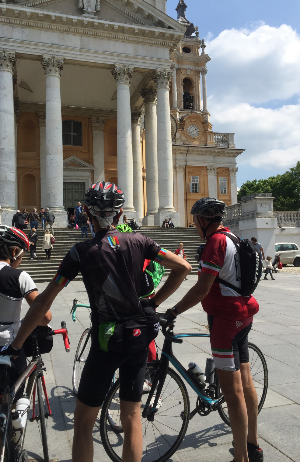 photo of a group of bicyclists in front of an old Italian building 