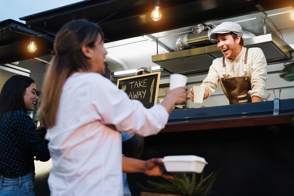 Italian man serving take away food inside food truck - Focus on chef face.