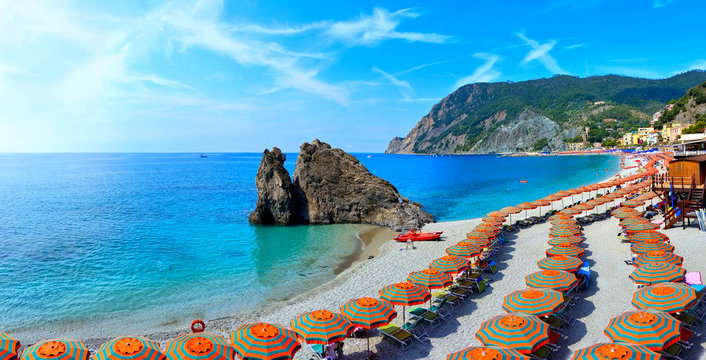 Beach lined with orange umbrellas on a sunny day in Italy