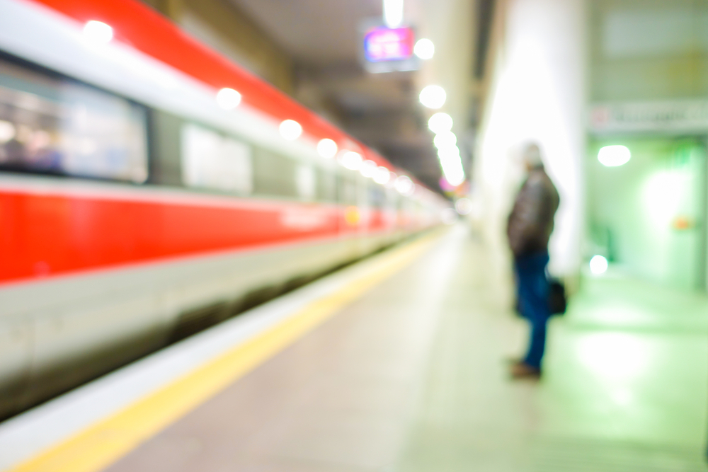 Blurred man waiting for high speed train in railway station - Defocused image - Original lights - Transportation, work and travel