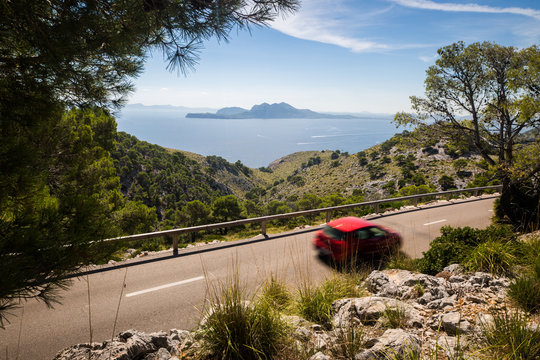 Red car driving along the coast of a highway in Mallorca