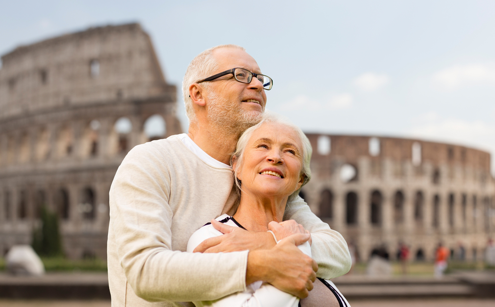 an older couple embraces in front of the Roman colosseum