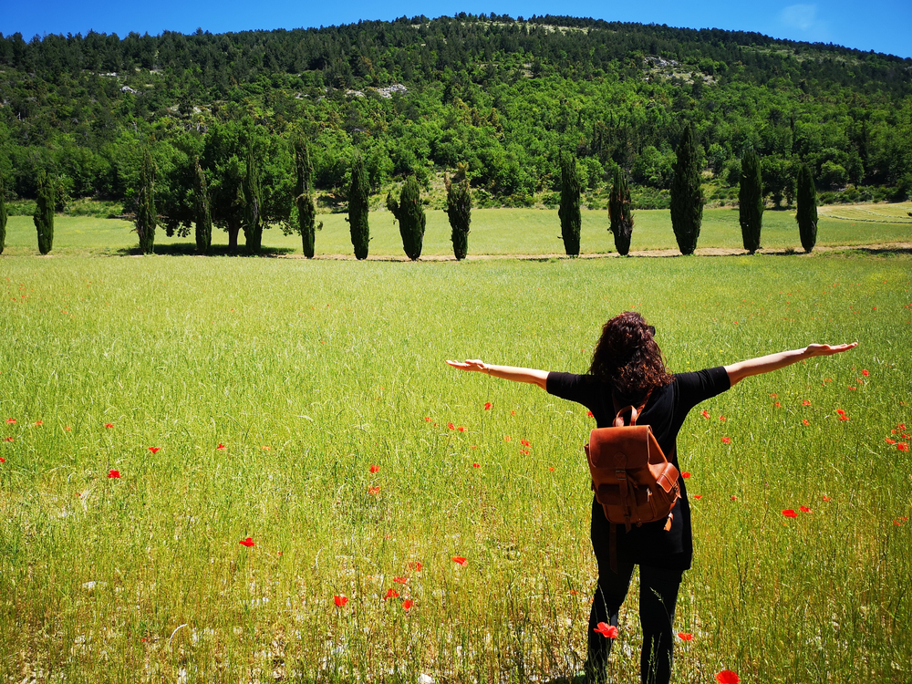 A rear view of a woman enjoying the beautiful landscape with open arms.