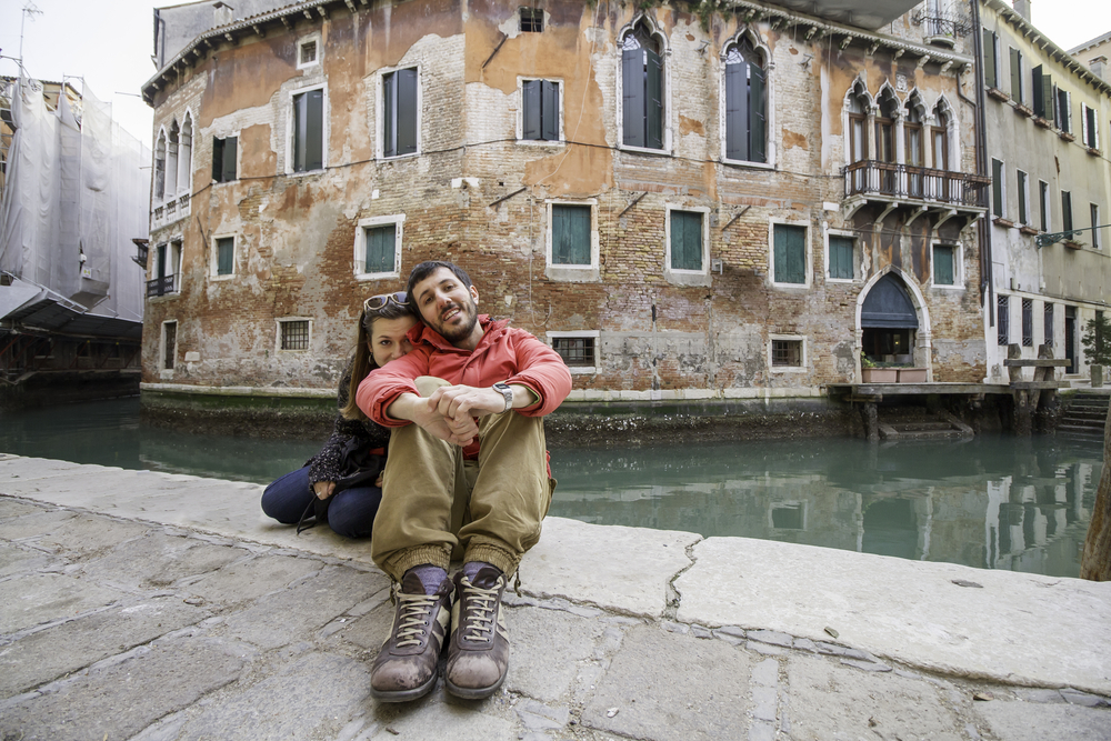 happy couple sitting on the side of the canal in Venice Italy