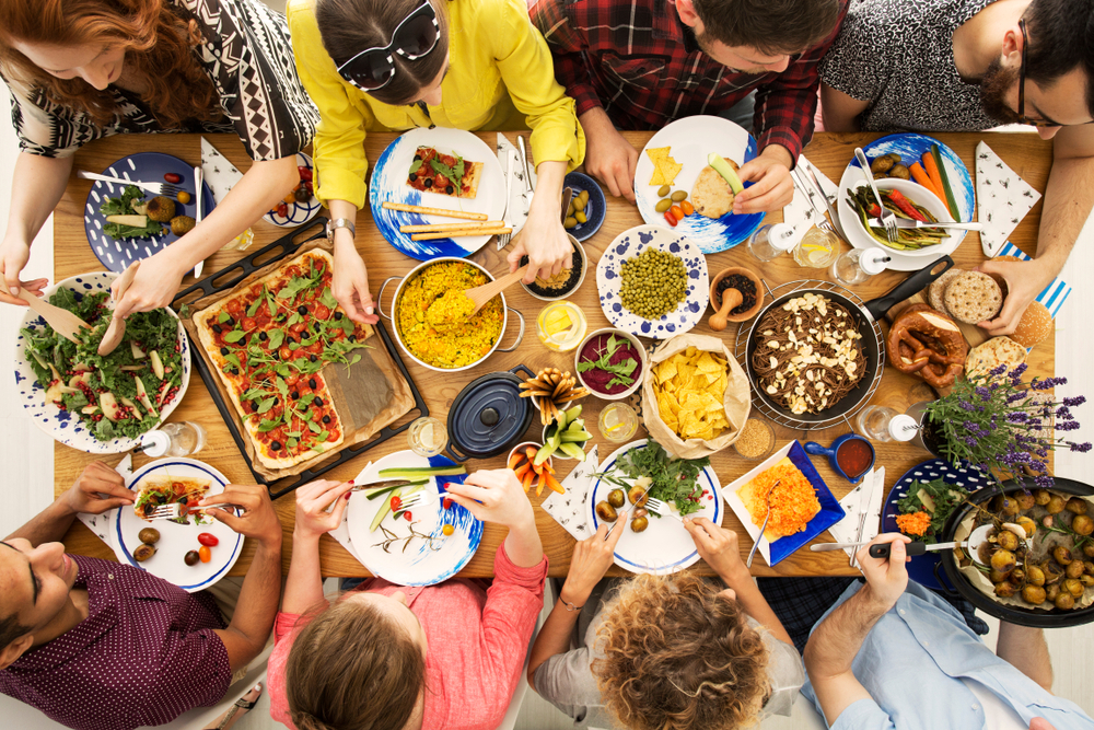 High angle of vegan friends eating a healthy dinner with hummus