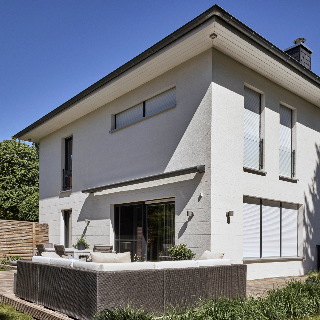 Modernes Haus mit Terrasse, dessen Rollläden geschlossen und Markise eingefahren ist.