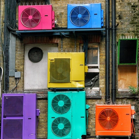 A photo of heat pumps or air conditioning units painted brightly on the outside of a building