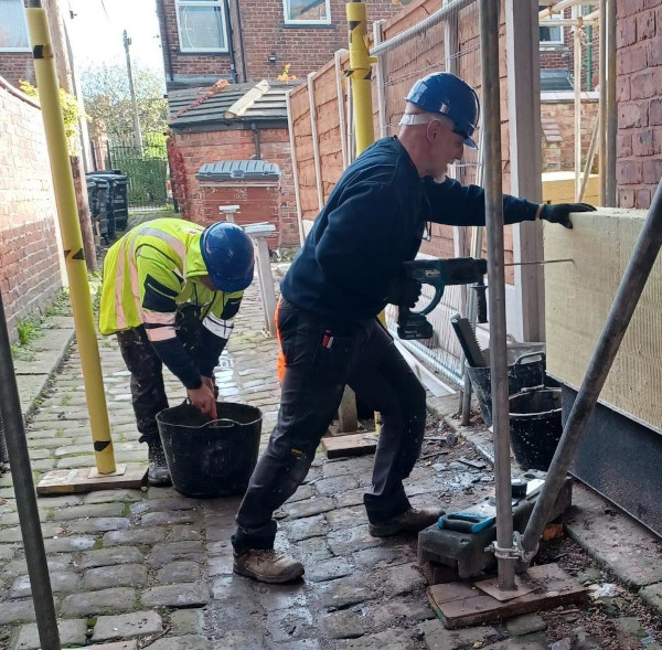 A photo of a worker fitting external wall insulation