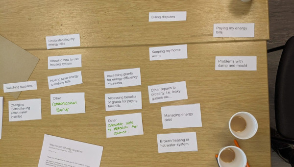 A photo of various printed energy advice issues laid out on a wooden table with two cups of tea