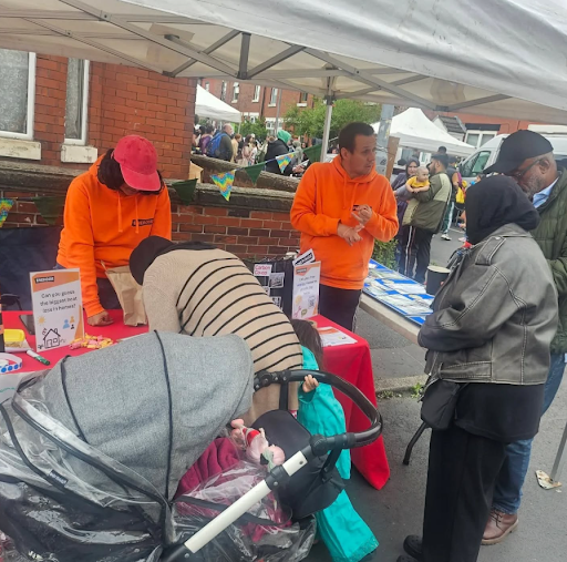 A photo of carbon co-op staff members in orange 'Energise' hoodies talking to people at a street stall