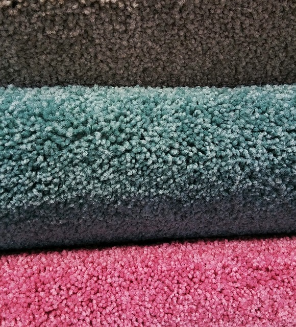 A photo of stack of carpets in pink, blue and grey.