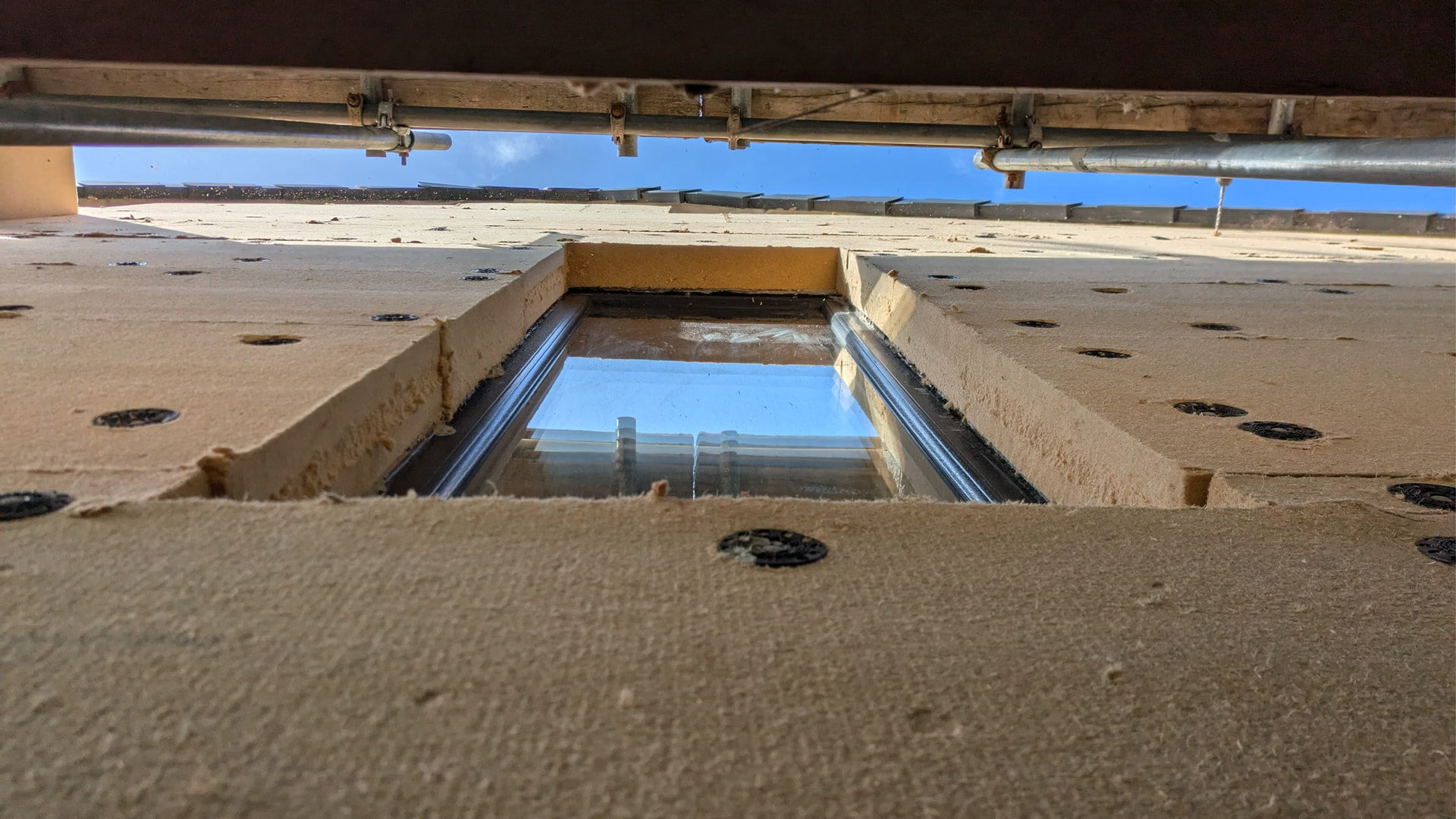 A photo looking at wood fibre, external wall insulation on a building wall, looking up to the sky.