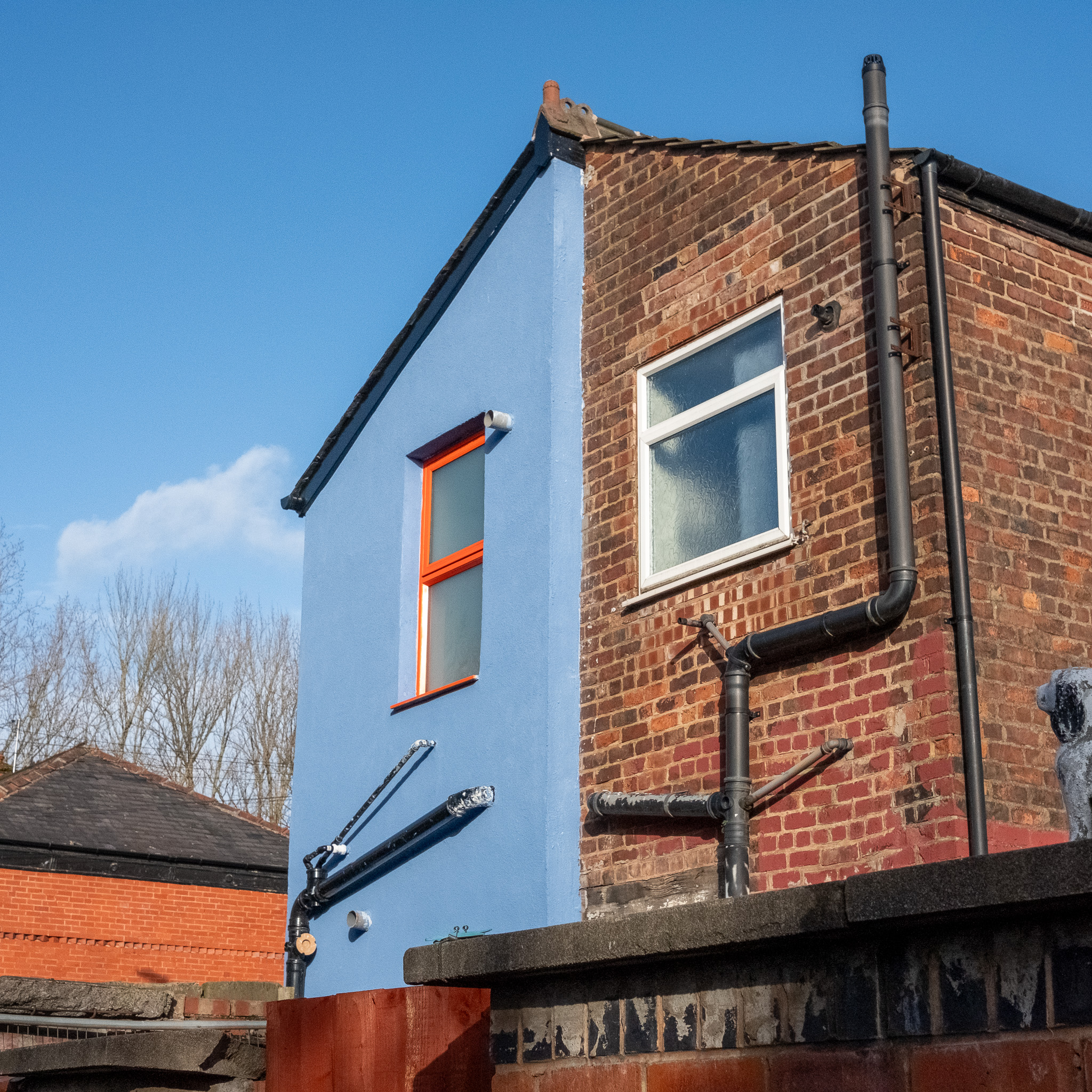 A picture of a terraced house with blue external wall insulation and orange window frames