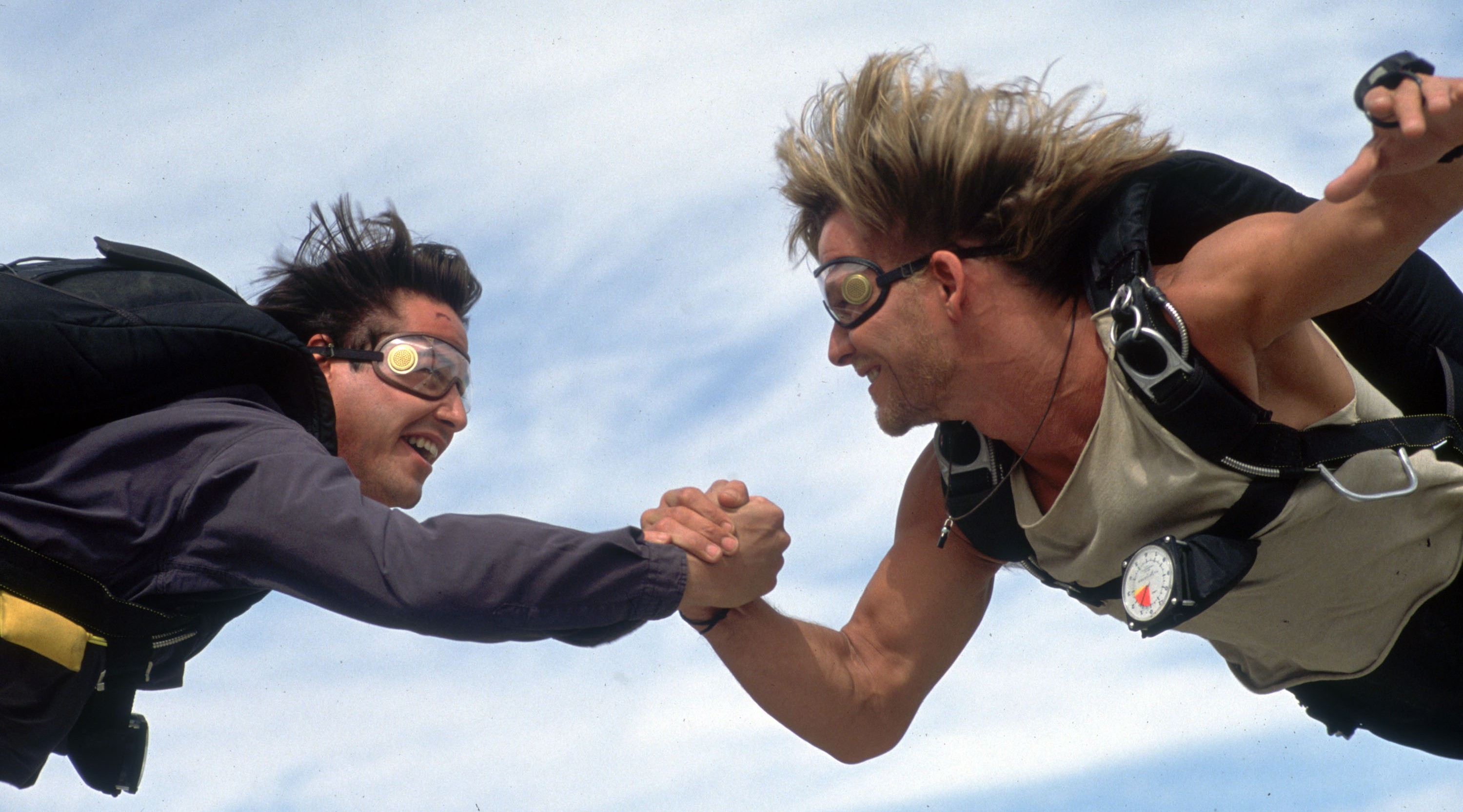 TWO MEN HOLDING HANDS DURING A SKYDIVE