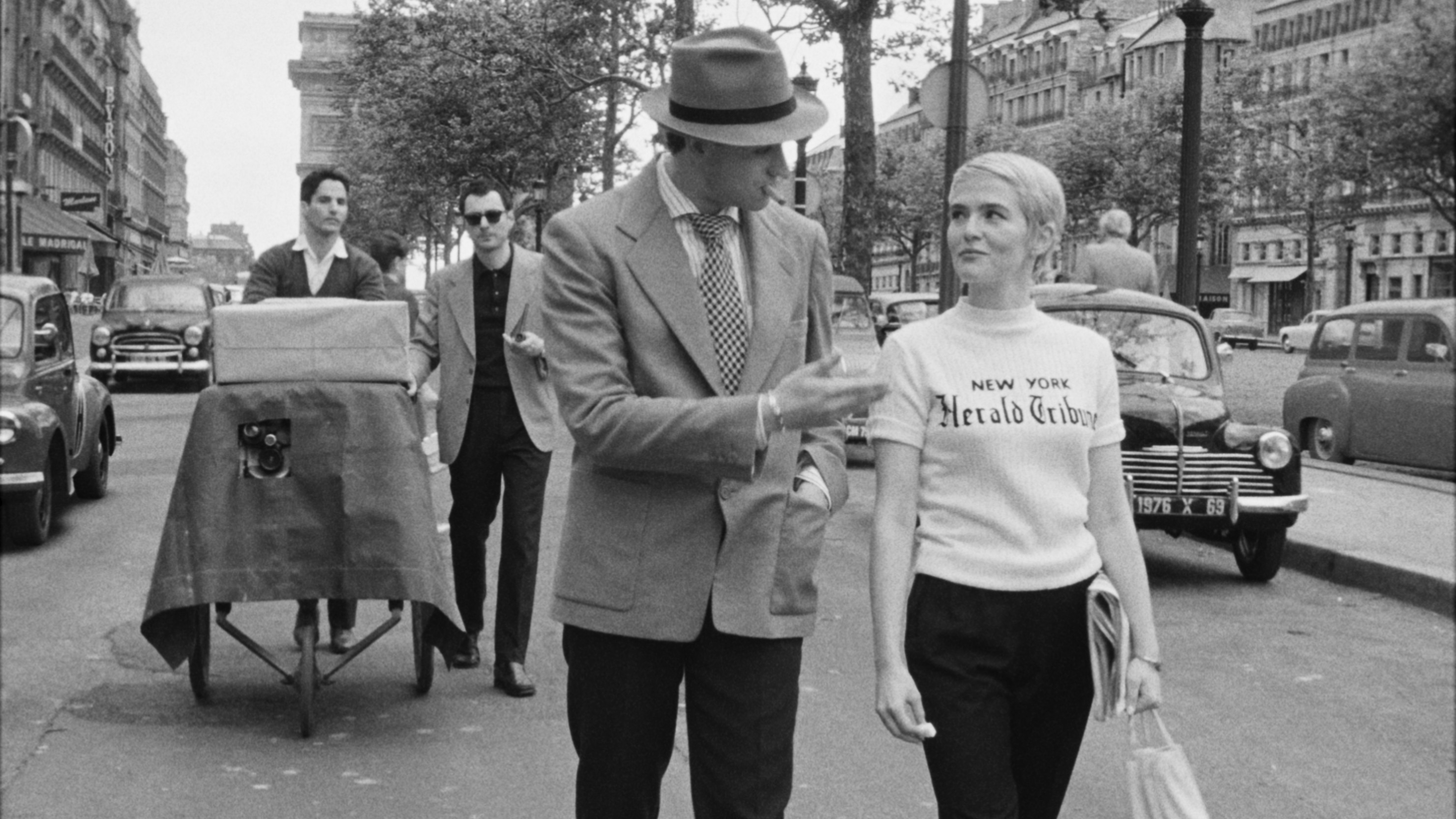 a stylish 1950s couple walk down a parisian boulevard
