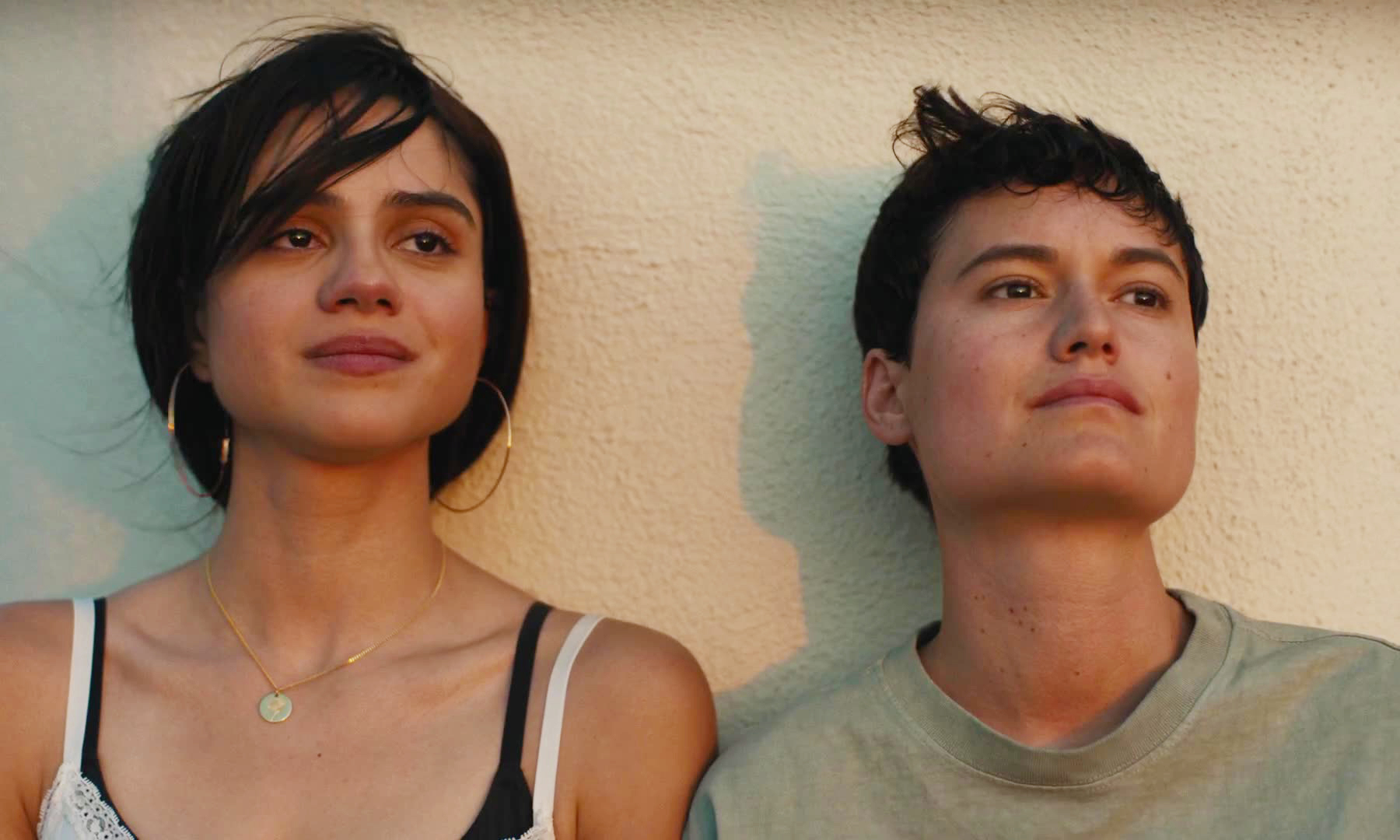 the co leads of in the summers sitting against a wall