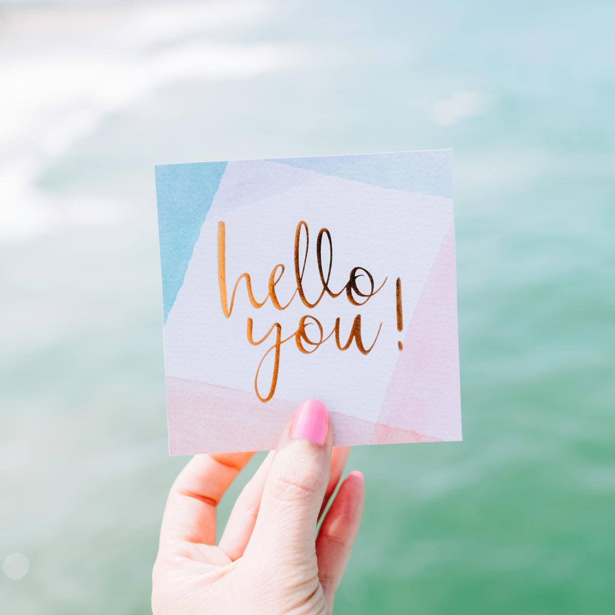 holding a sticker saying, "hello you!"