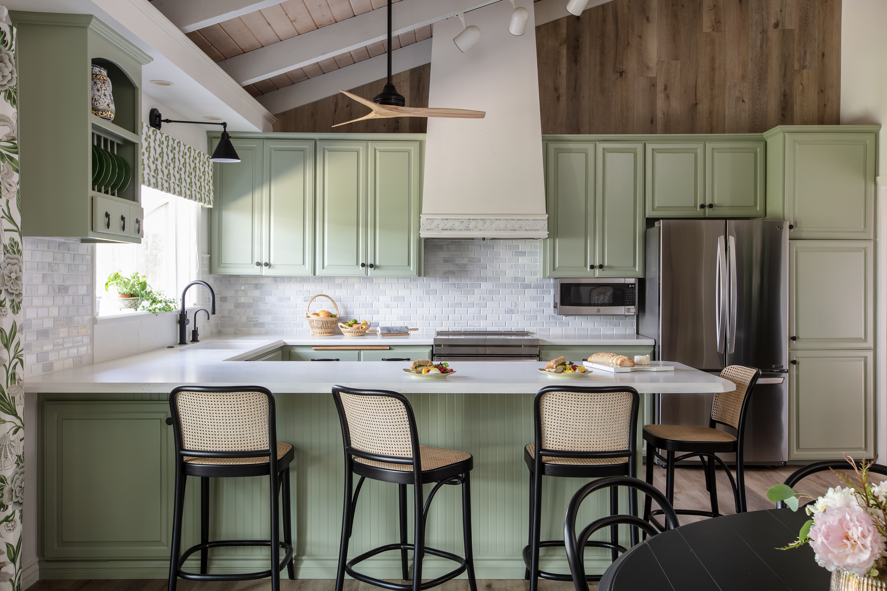 Kitchen with bar stools, green cabinets, and ceiling fan