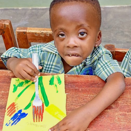 a 5 year-old, missing his two front teeth, painting a colorful picture of flowers, using a fork as a paint brush.