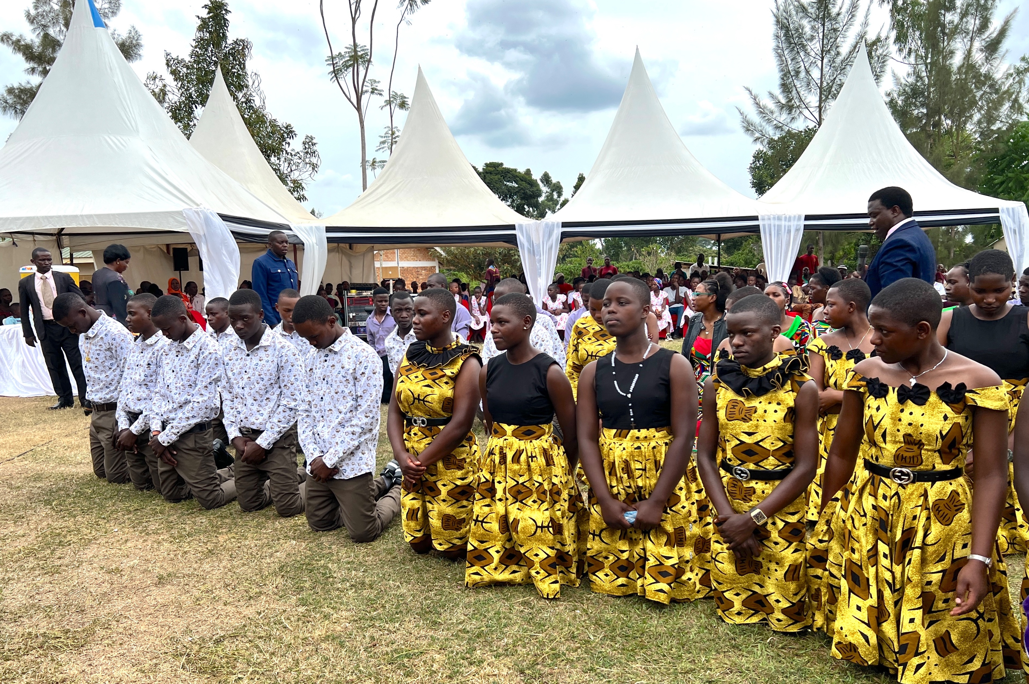 Ugandan teenagers in colorful clothing kneeling for a blessing