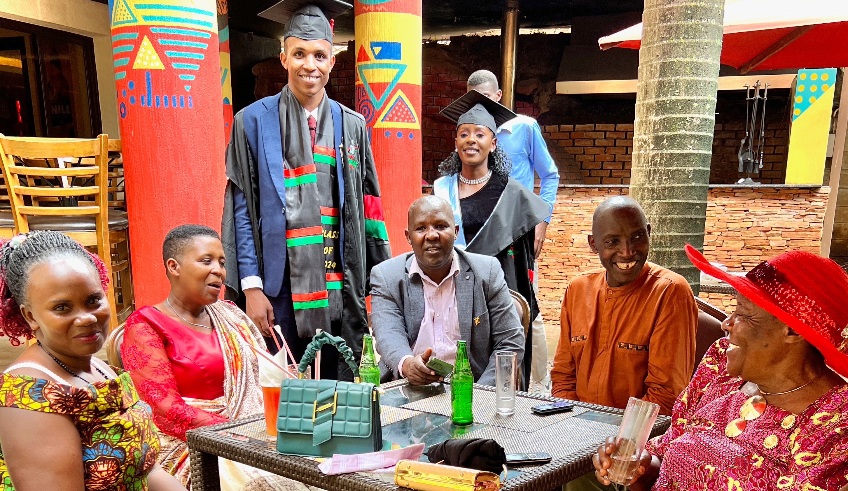 Colorful group of Ugandans—two dressed in graduation caps and gowns