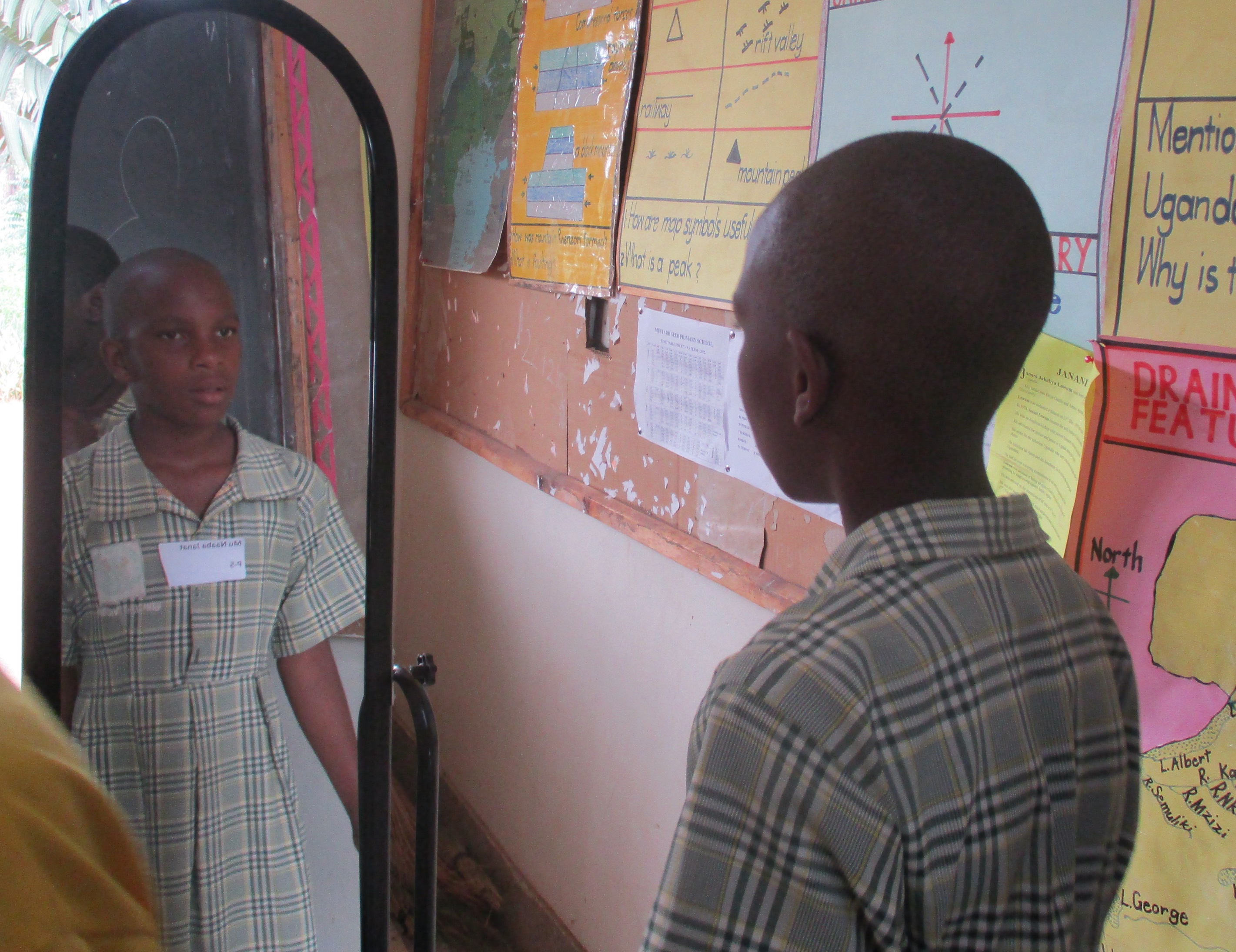 Ugandan 10 year-old girl looking at herself in a full-length mirror