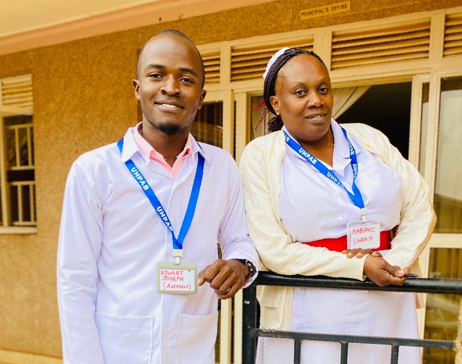 Three young Ugandan men with an older man with beautiful trees and shrubs in the background