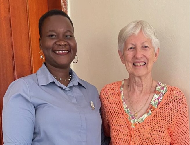 A well-dressed Uganan woman smiling next to an elderly, well-dressed American woman