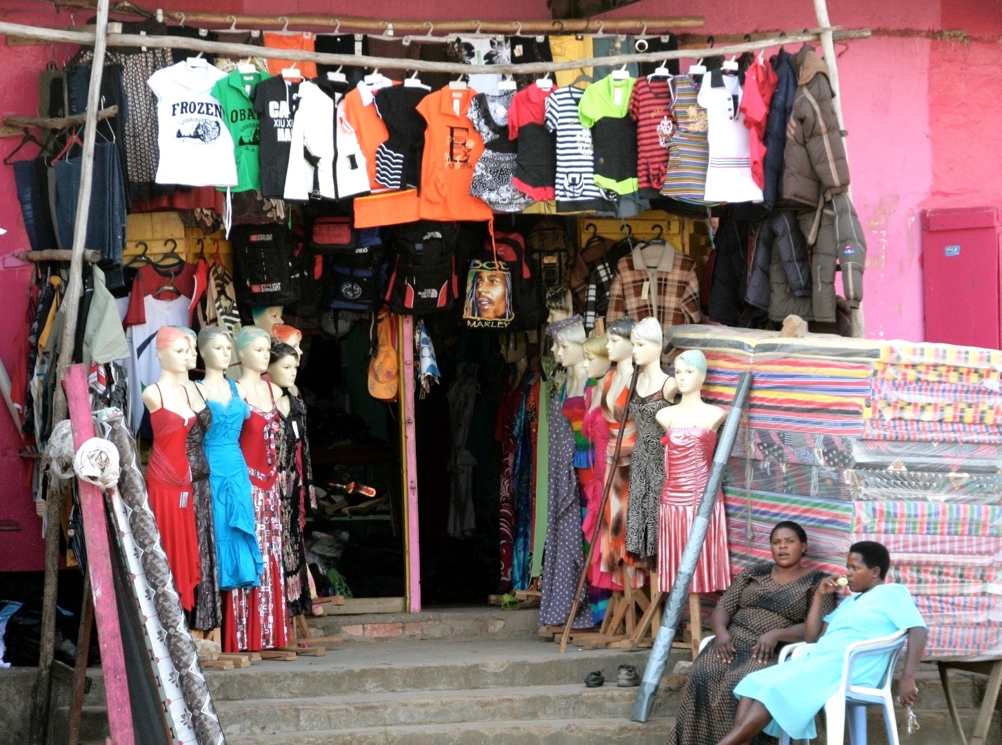 Colorful small shop with clothes and mattresses on the steps outside.  