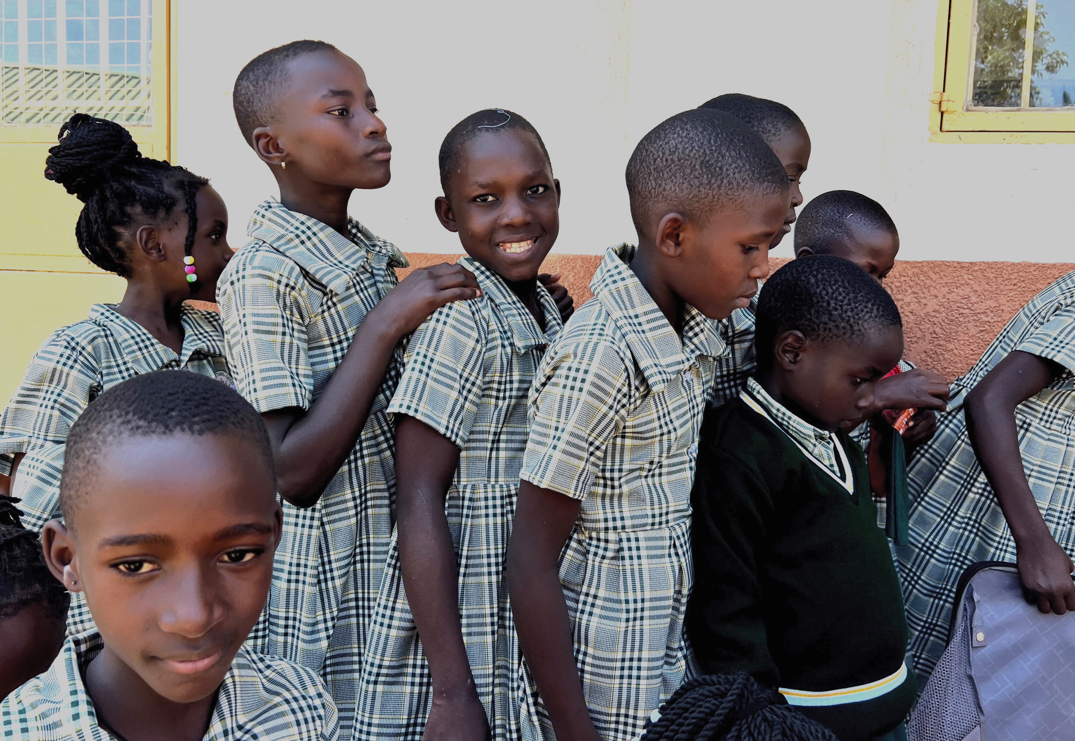 Young Ugandan students lined up in front of a suitcase full of dark green socks.