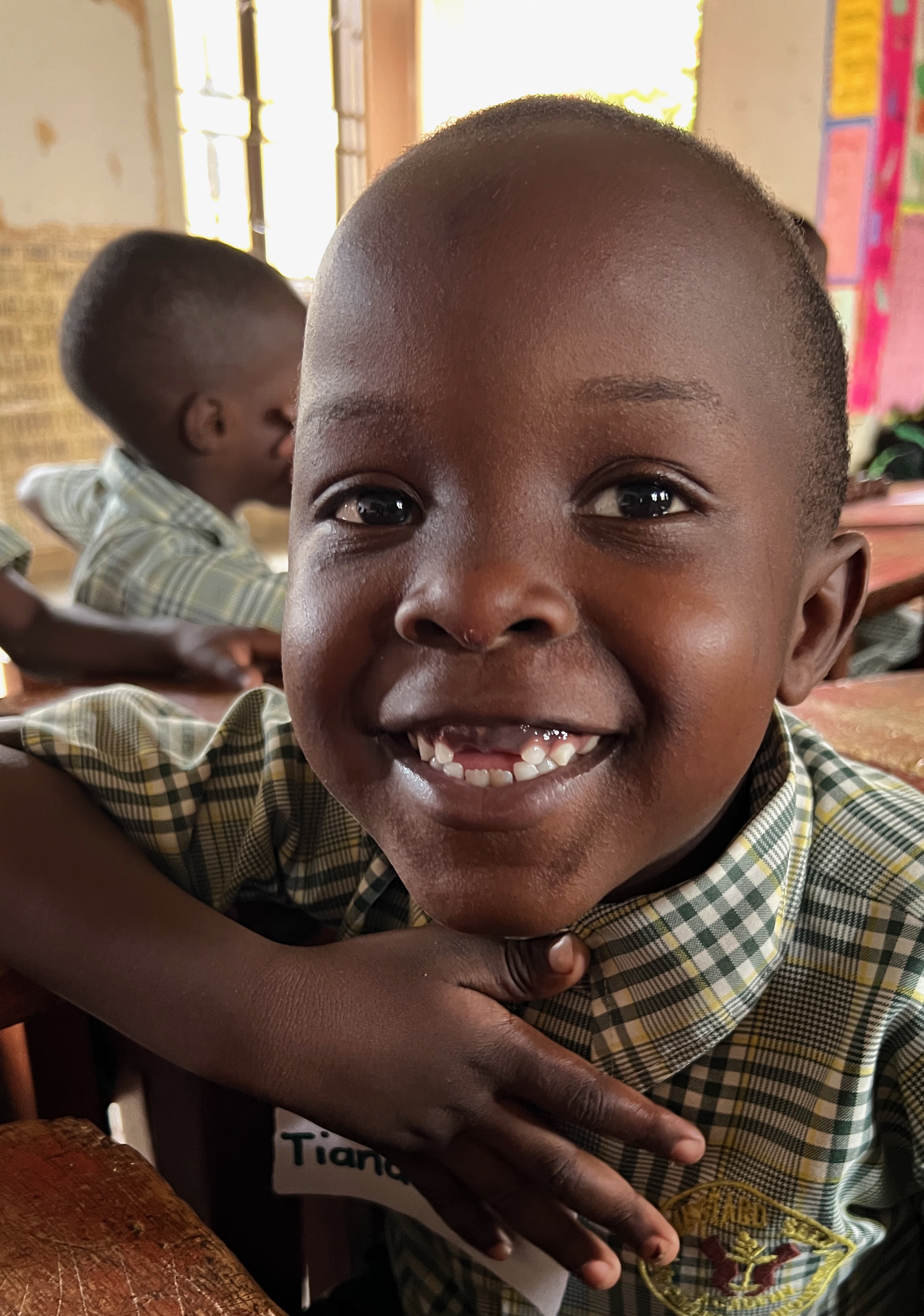Ugandan nursery school child with a big smile and two teeth missing