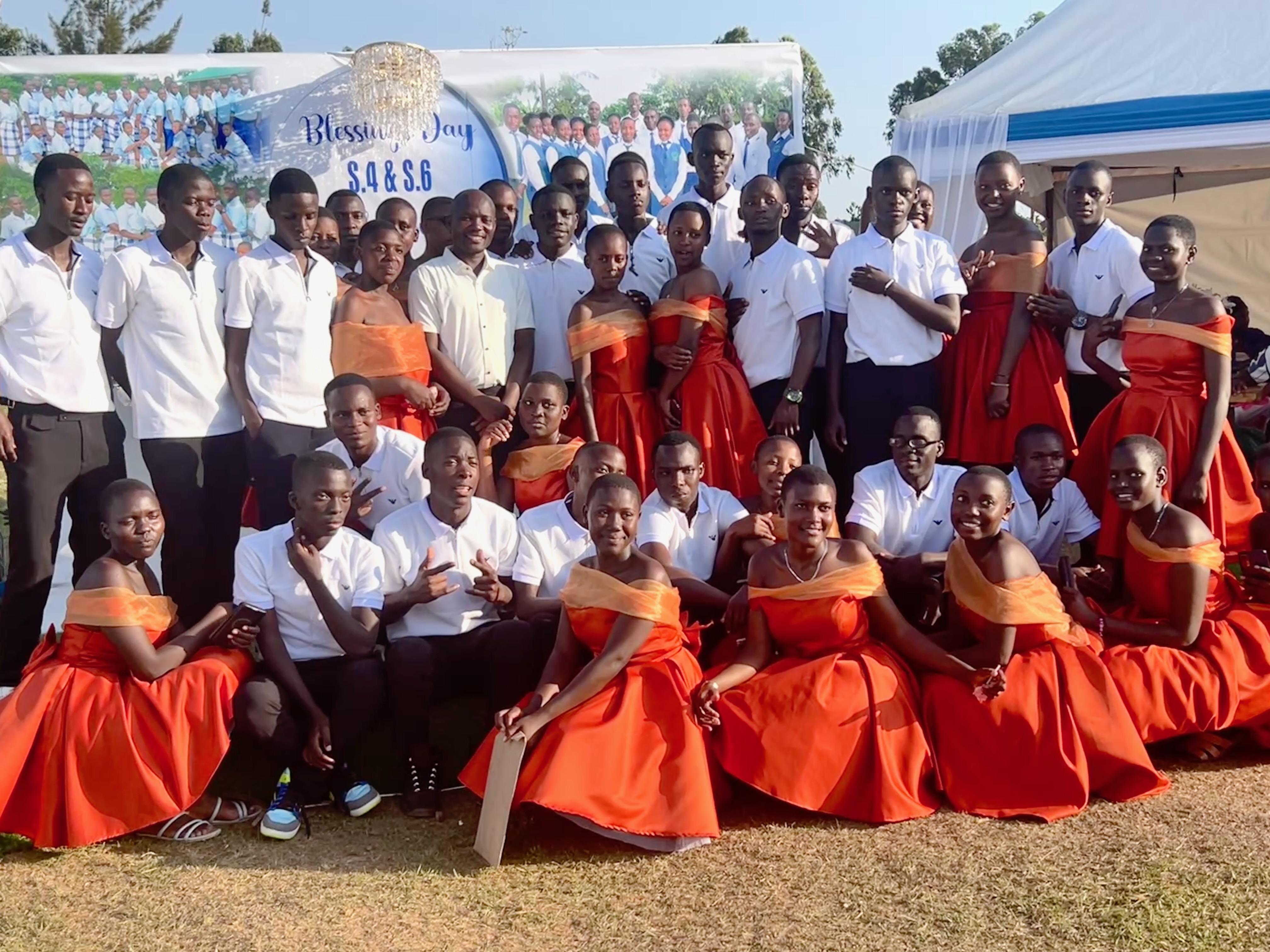 Class of well-dressed high school students in front of a Blessing Day display