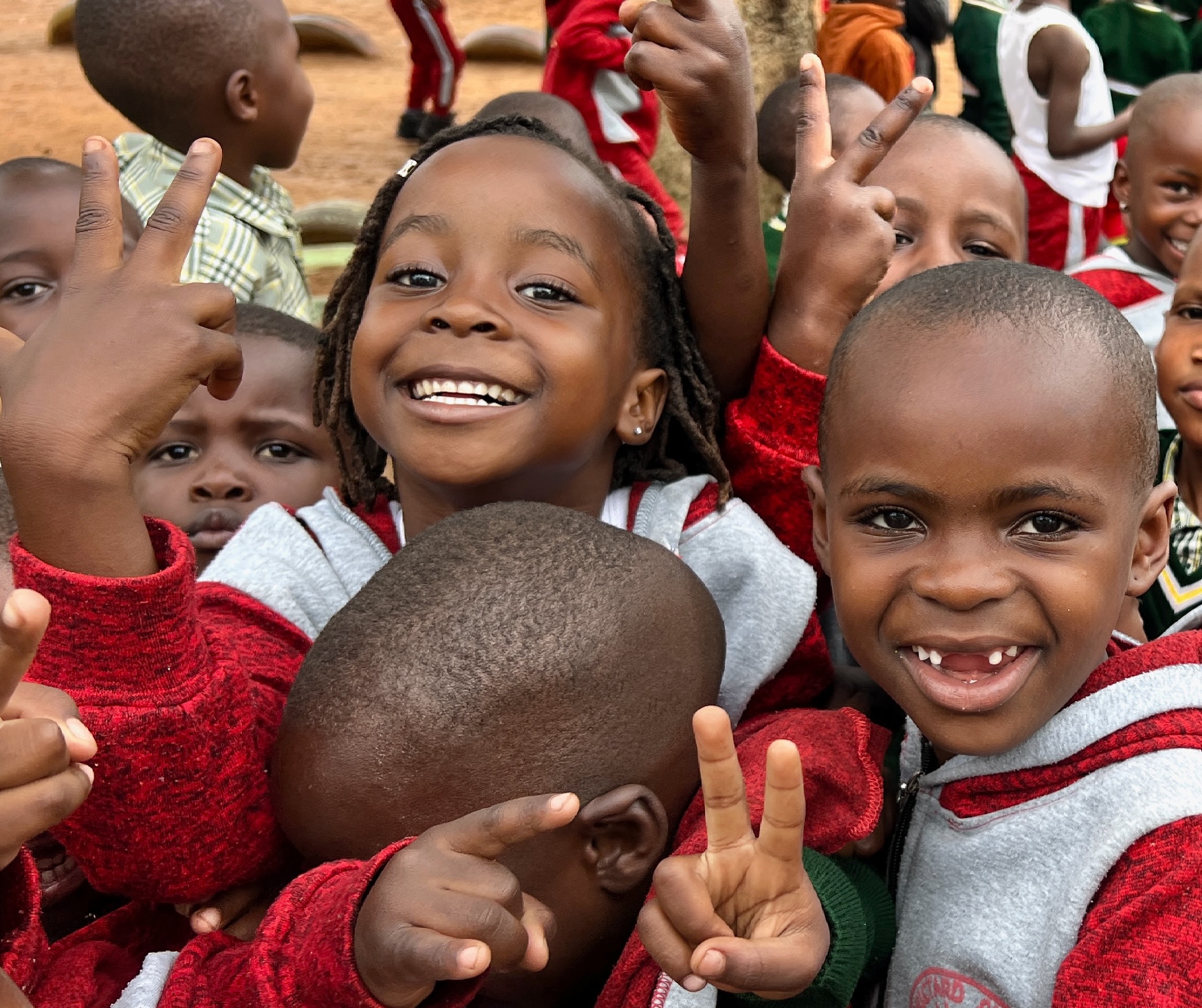a small mob of nursery school children, dressed in red tracksuits, giving the peace sigh