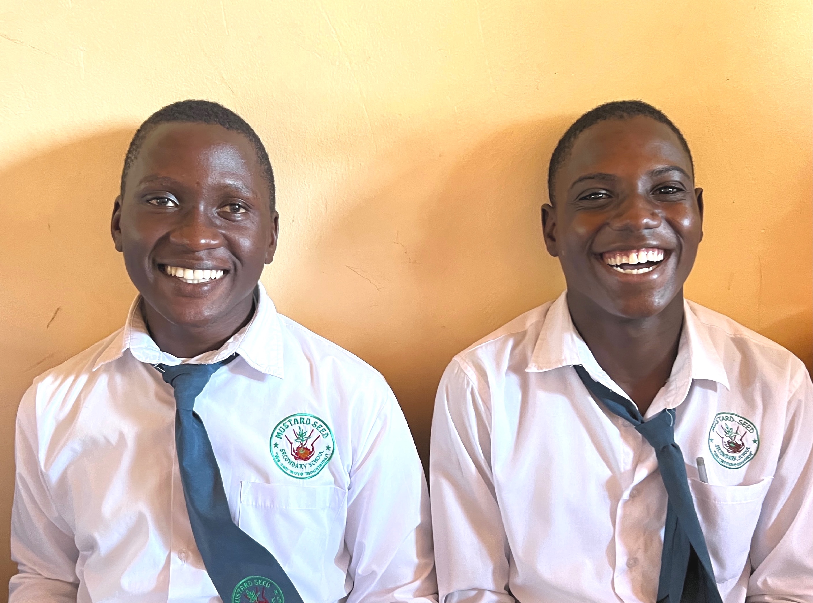 Two young men in shirts and ties, laughing joyfully.
